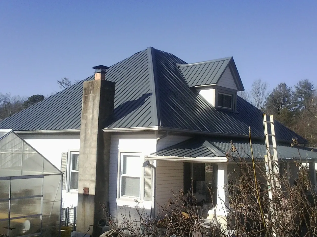 Dark blue standing seam metal roof on a white farmhouse with dormer — Slate & Tile Roof Repair by Roofing Brothers in Mooresburg