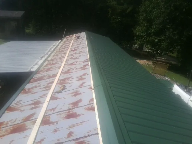 Old rusted panels beside newly installed green metal roofing — Wind Damage Roof Repair by Roofing Brothers in Mooresburg