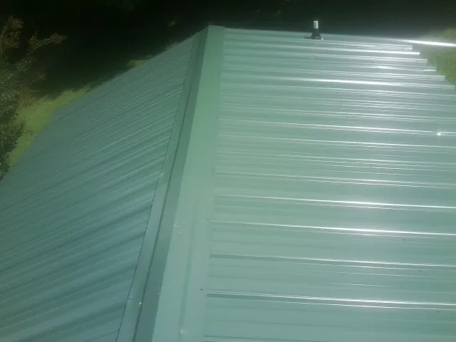 New green metal panels meeting at the ridge of a roof — Flat Roof Repair work by our crew in Mooresburg