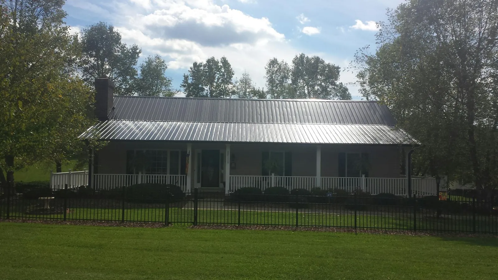 Gray metal roof on a brick ranch with a full width front porch — Gutter Guard Installation work by our crew in Mooresburg