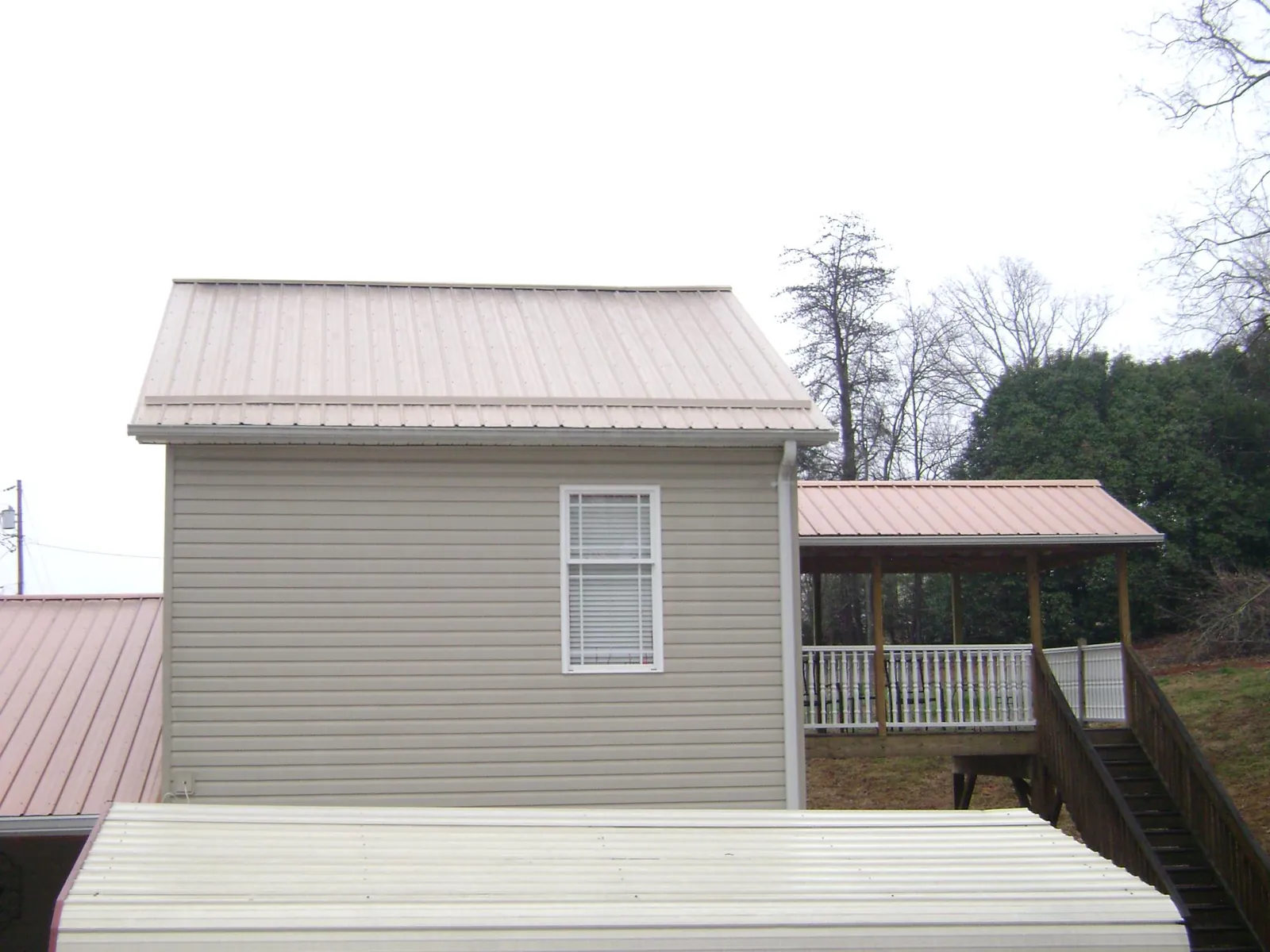 Tan metal roofs on a two story addition and attached porch, from a Roof Replacement job in Mooresburg
