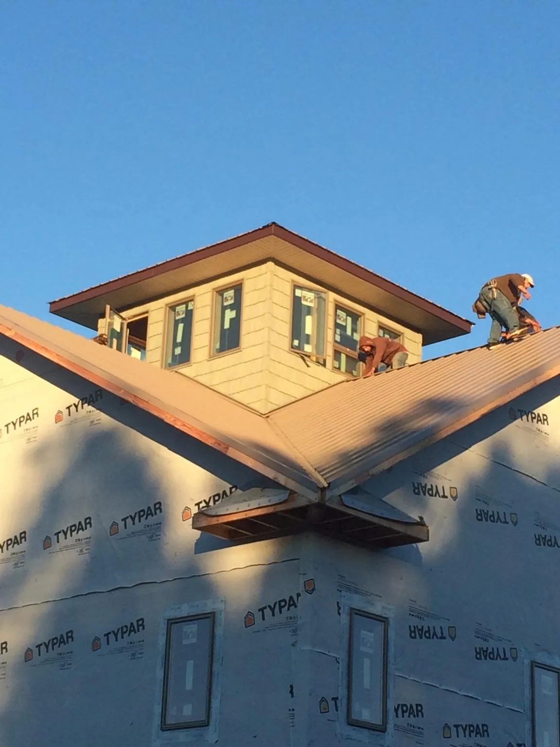 Roofers working around a rooftop cupola on a new metal roof at sunset — Roof Waterproofing in Mooresburg by Roofing Brothers